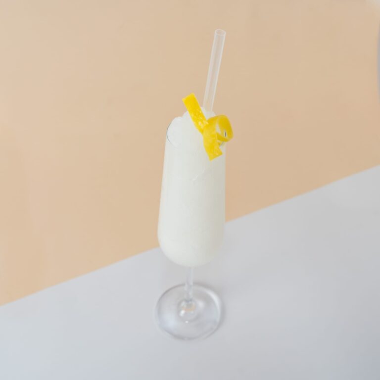 Cóctel congelado de French 75, adornado con una rodaja de limón y una cereza en una copa de champán.