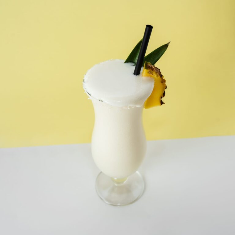 Cóctel de piña colada congelado servido en vaso decorado con rodaja de piña y cereza.