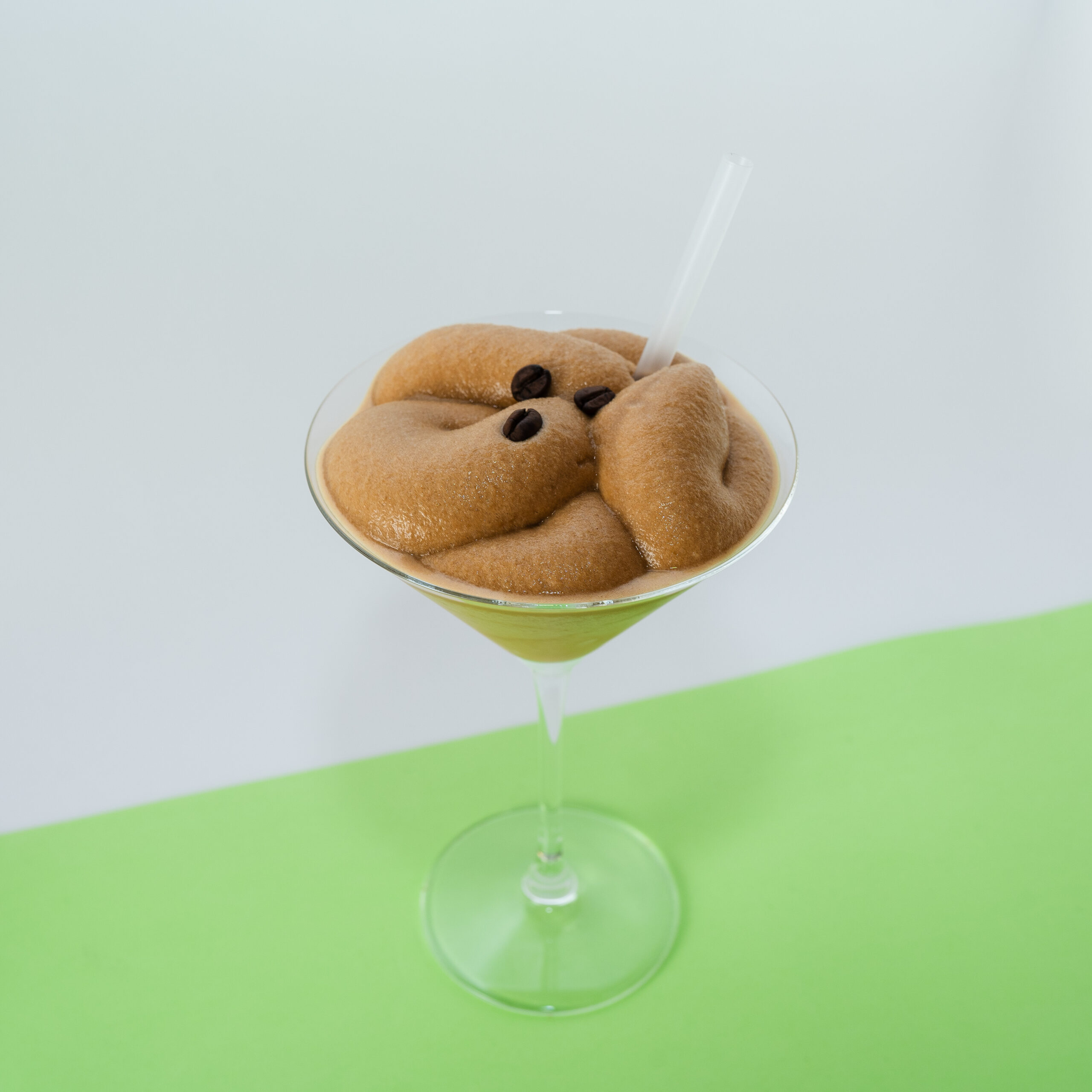 Un elegante Frozen Espresso Martini servido en una copa de cóctel, con una textura cremosa y escarchada, decorado con granos de café y un ligero espolvoreado de cacao.